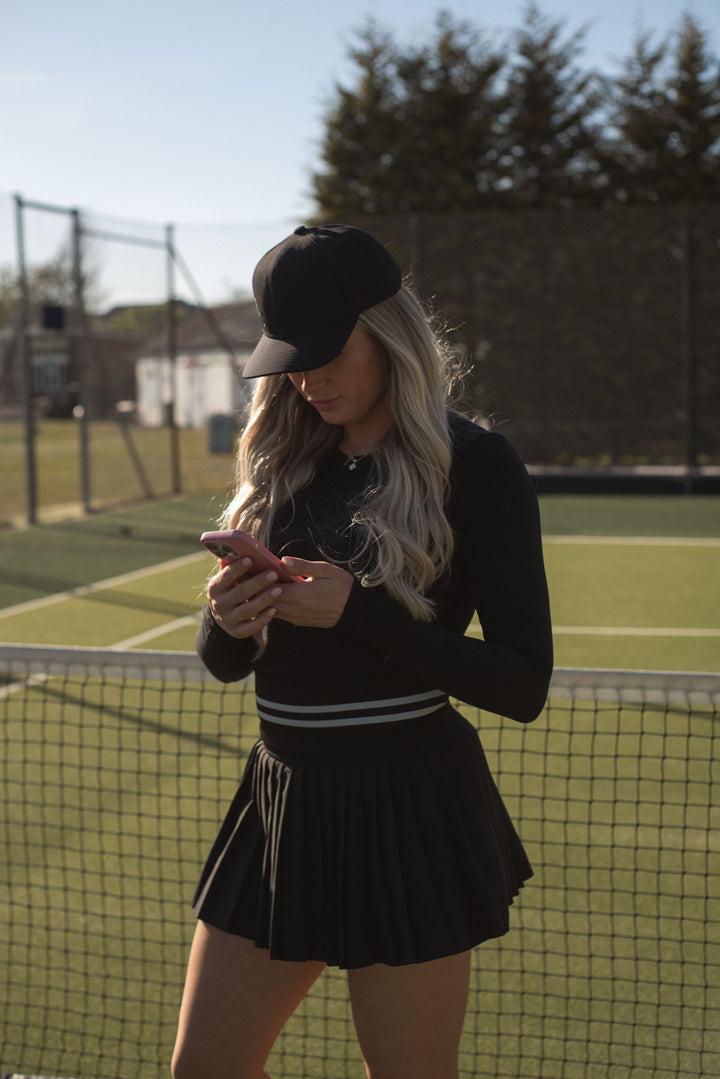 High-waisted black skort with stretch fit, preppy athletic style
