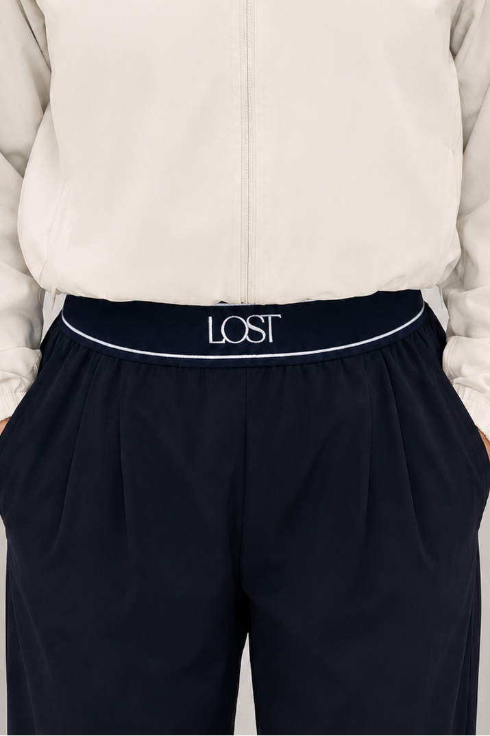 Person wearing a cream jacket and navy pants with 'LOST' branding 